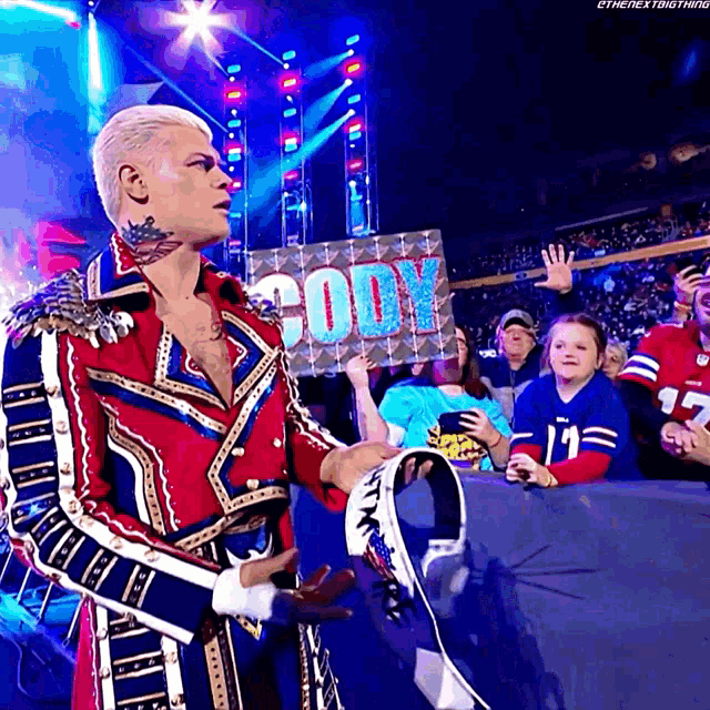 a wrestler holds a sign that says cody in front of a crowd