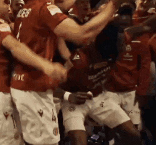 a group of soccer players wearing red jerseys and white shorts celebrate