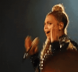 a woman in a black and gold dress is laughing while holding her face .