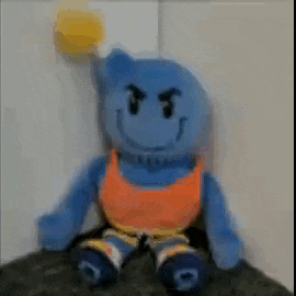 a blue stuffed animal with a smiley face on it is being held by a person .
