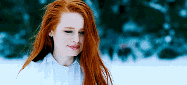 a woman with long red hair is standing in the snow .