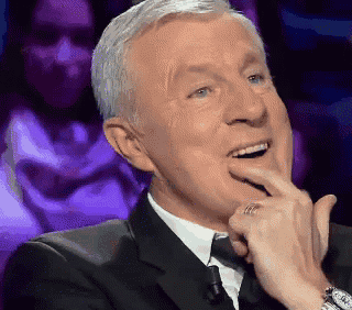 a man in a suit and tie is smiling with his hand to his chin