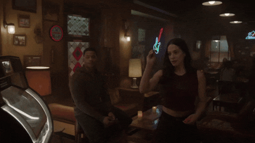 a man and a woman are standing in a dark room with a sign that says ' a & a ' on it