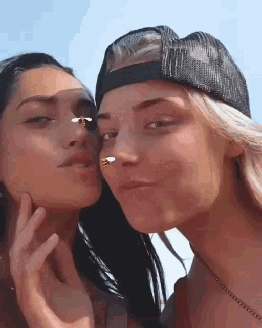 two women are posing for a picture and one of them has a bee on her nose