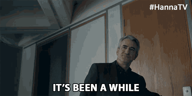 a man in a suit says it 's been a while in front of a door