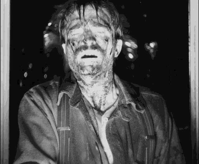a black and white photo of a man with his face covered in blood