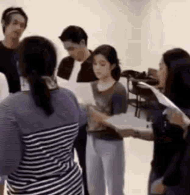 a group of people are standing in a room holding papers .