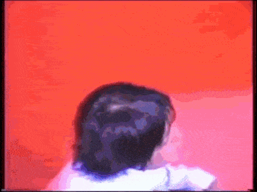 a woman is standing in front of a red wall