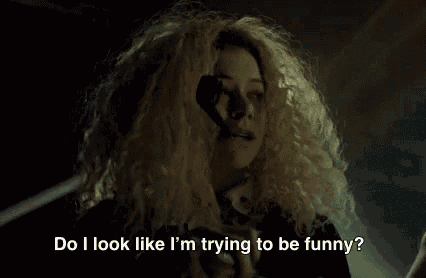 a woman with curly blonde hair is saying do i look like i 'm trying to be funny