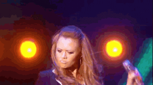 a woman is singing into a microphone in front of a purple background