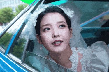 a woman in a wedding dress is looking out the window of a car