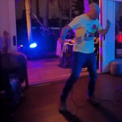 a person is dancing in a dark room with purple lights