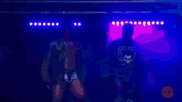 two men are dancing on a stage with one wearing a shirt with a skull and crossbones on it