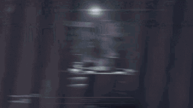 a blurry picture of a dark room with a few lights coming out of the window .