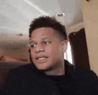 a young man is sitting on a couch in a living room making a funny face .