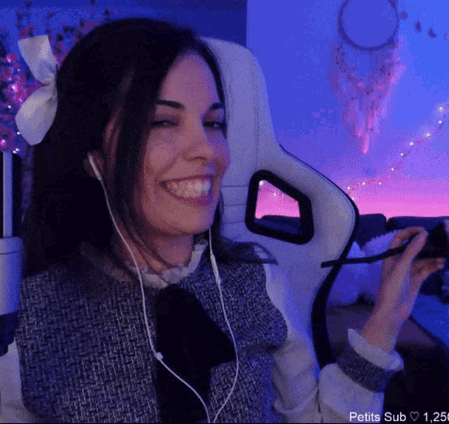 a woman wearing headphones and a bow in her hair is smiling while sitting in a chair