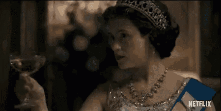 a woman in a tiara is holding a glass of wine in her hand .