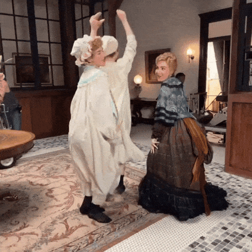 a woman in a dress is kneeling down and giving a high five to another woman in a white dress