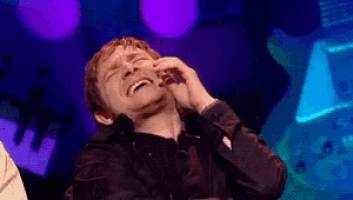 a man is laughing with his hand on his face in front of purple lights