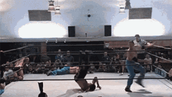 two men are wrestling in a ring with a referee