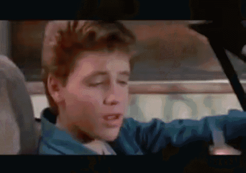 a young boy in a blue jacket is sitting in the back seat of a car with his eyes closed .