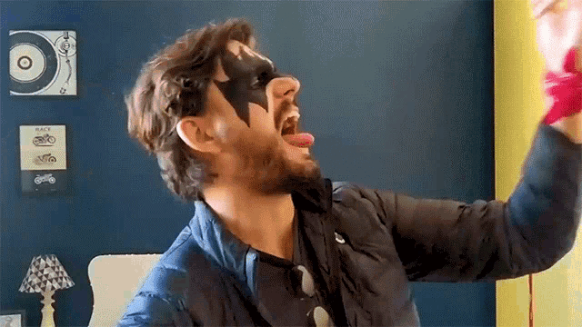 a man wearing a black mask with a star on it is sticking out his tongue