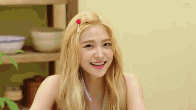 a close up of a woman with blonde hair and a red flower in her hair .