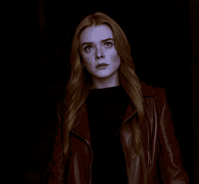 a woman with long red hair wearing a red leather jacket