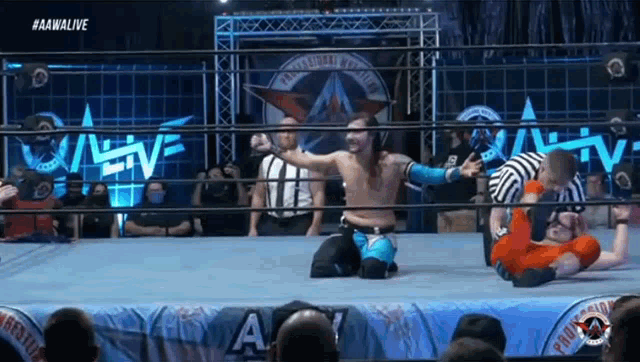 a wrestler is kneeling down in a wrestling ring while another wrestler is being pinned down