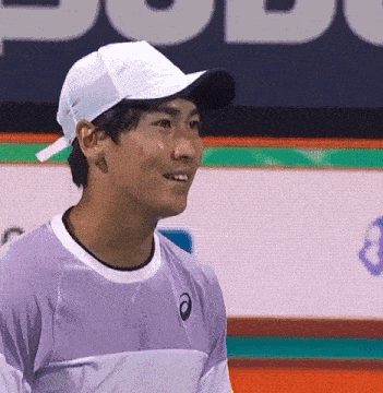 a man wearing a hat and a purple shirt is smiling .
