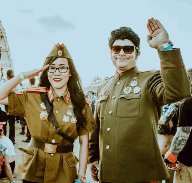 a man and a woman are dressed in military uniforms and saluting