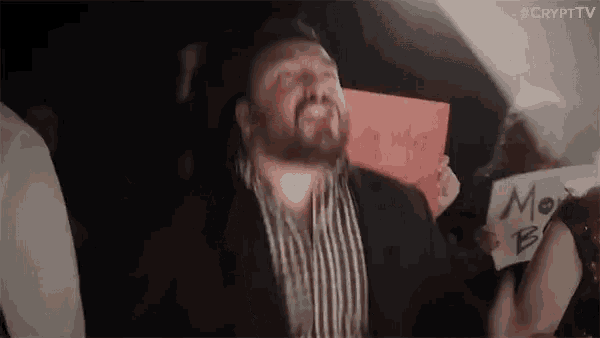 a man in a suit and striped shirt is holding a sign that says `` my idea '' .