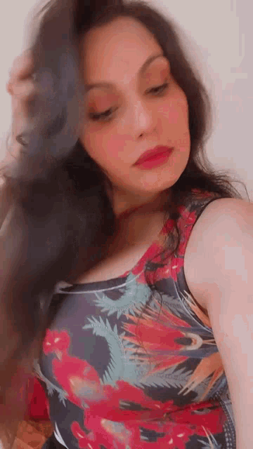 a woman in a floral tank top is taking a picture of herself