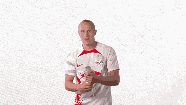 a man wearing a red bull shirt is holding a can