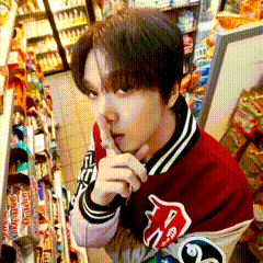 a man in a red jacket is covering his mouth with his hand in a grocery store
