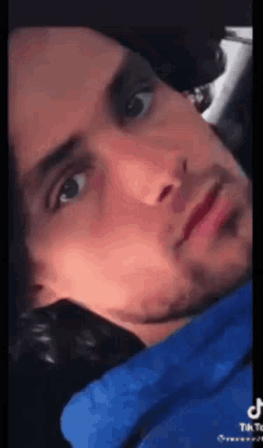 a close up of a man 's face with a blue shirt on