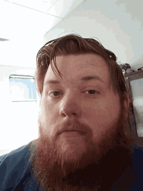 a man with a beard looks at the camera