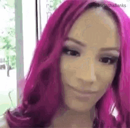 a woman with pink hair is making a funny face .