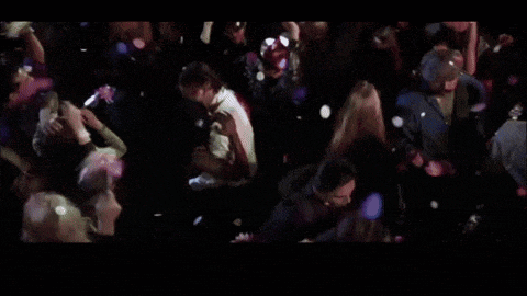 a crowd of people dancing in a dark room with confetti falling