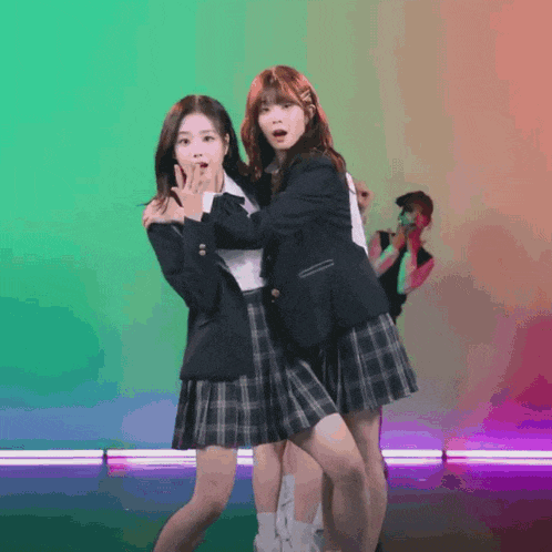 two girls in school uniforms are dancing together on a stage
