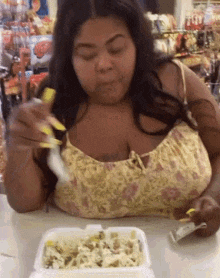 a woman is sitting at a table with a styrofoam container of food .