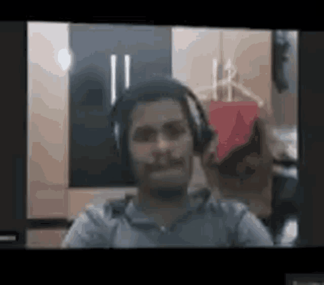 a man wearing headphones is taking a selfie while sitting in front of a computer screen .