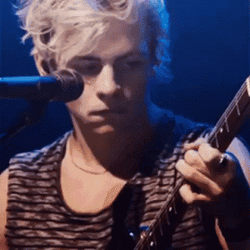 a young man is playing a guitar in front of a microphone .