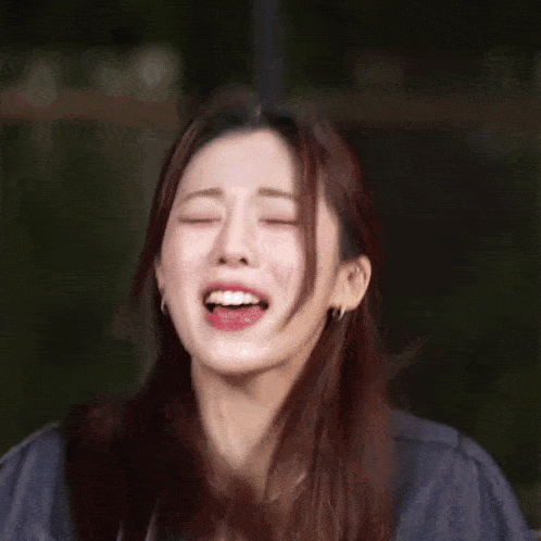 a close up of a woman laughing with her mouth open and her eyes closed .