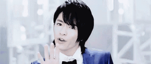 a young man in a blue suit and bow tie is standing in a room with mirrors .