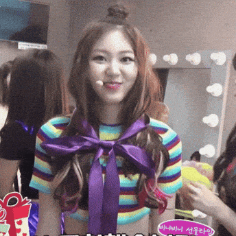 a woman in a striped shirt with a purple bow around her neck stands in front of a mirror