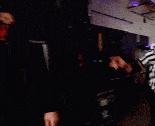 two men are standing next to each other in a dark room and one of them has a tattoo on his shoulder that says k on it