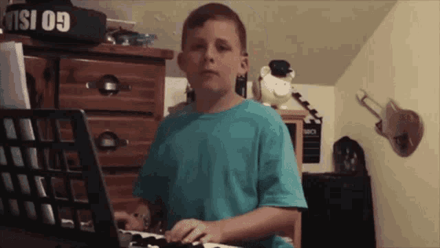 a boy in a blue shirt is playing a keyboard in front of a sign that says go island