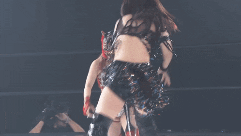 a woman in a black dress is dancing in a ring with a tiger mask on