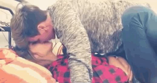 a man is kissing a woman on the neck while laying on a bed .